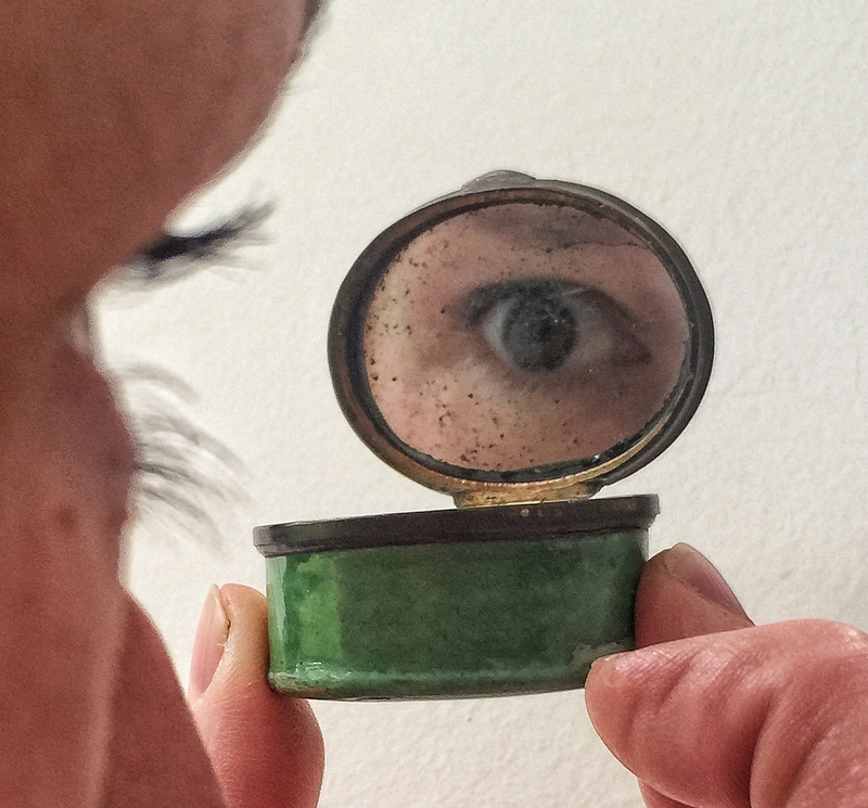 Close-up of eye reflected in mirror inside lid of an open patch box