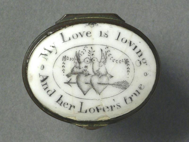Lid of a white enamel patch box with motto round the edge and in the centre, two birds on two hearts