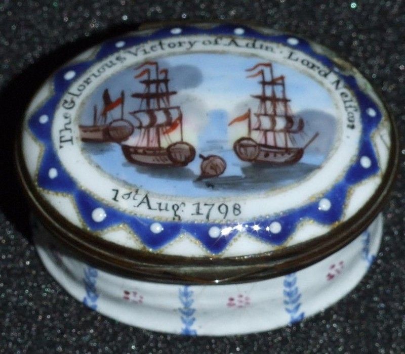 A round patch box with a seascape showing two ships in full sail and another ship between them almost fully sunk
