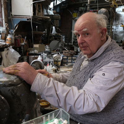 Man in profile sitting at workbench with hand on a lathe