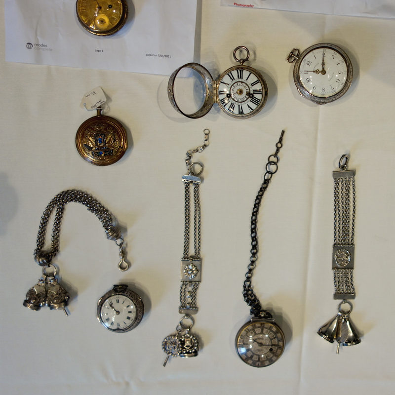 Various old pocket watches and watch chains laid out on a table.